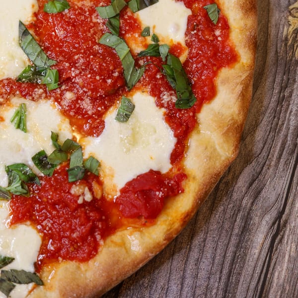 Close-up of a Sorella's Pizza & Pasta Margherita pizza with fresh basil, mozzarella, and tomato sauce.